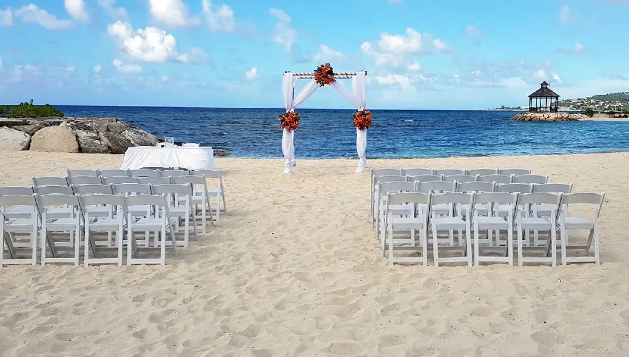 Barracuda Beach wedding ceremony with white chairs and arch at Secrets Wild Orchid, Montego Bay