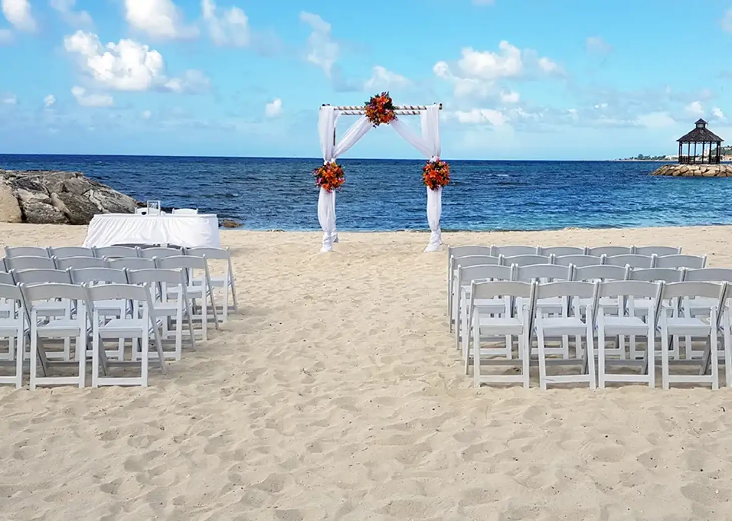 Barracuda Beach wedding ceremony with white chairs and arch at Secrets Wild Orchid, Montego Bay