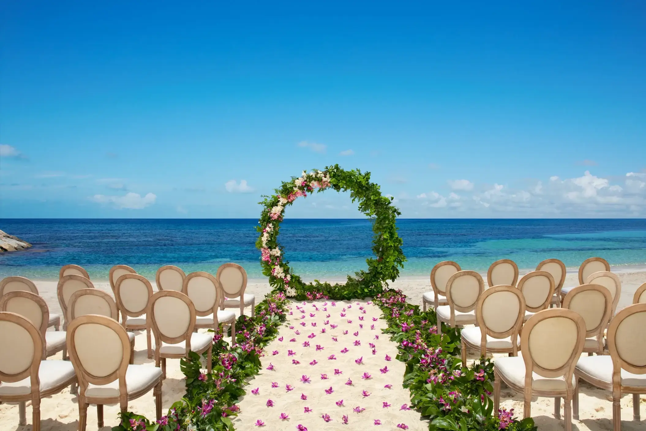 Beachfront wedding ceremony with a circular floral arch at Secrets St James, Montego Bay