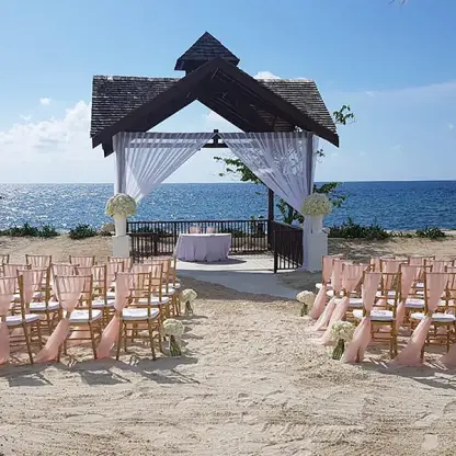 Beachfront wedding ceremony setup with pink sashes at Secrets St James, Montego Bay