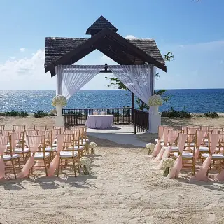 Beachfront wedding ceremony setup with pink sashes at Secrets St James, Montego Bay