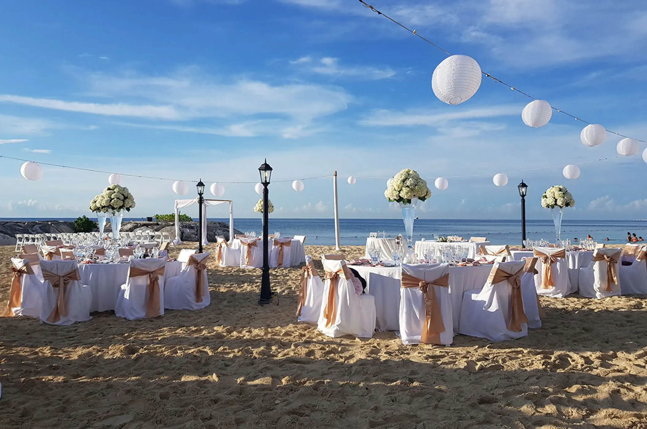 Beach wedding reception with white lanterns and floral centerpieces at Secrets St James, Montego Bay
