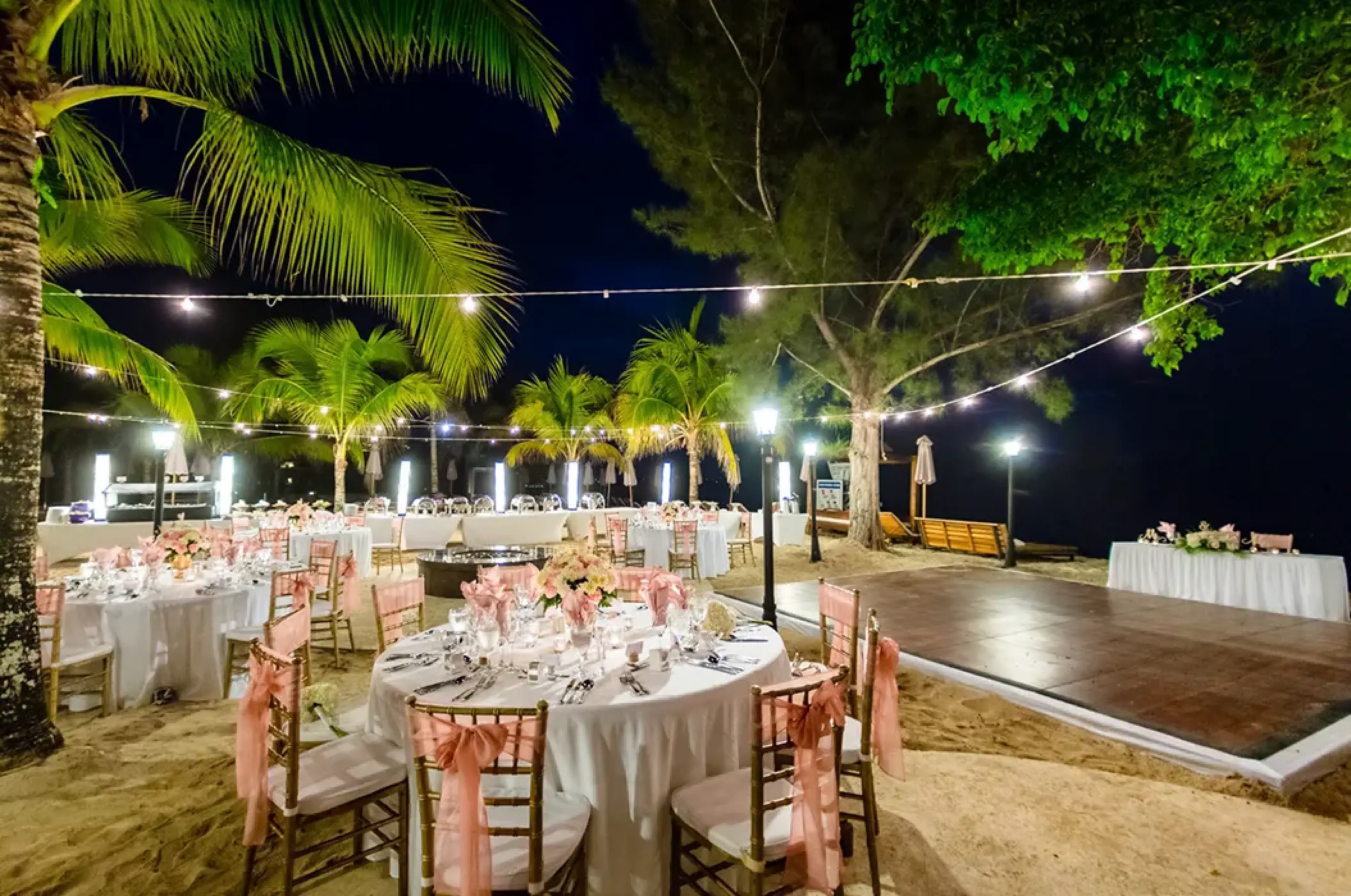 Beachfront wedding reception with string lights and dance floor at Secrets Wild Orchid, Montego Bay