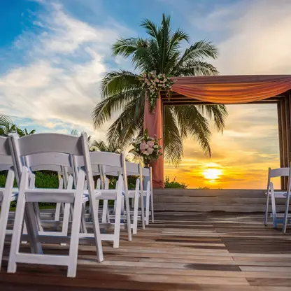 Wooden deck wedding ceremony at sunset with a pink draped arch at Secrets Wild Orchid, Montego Bay