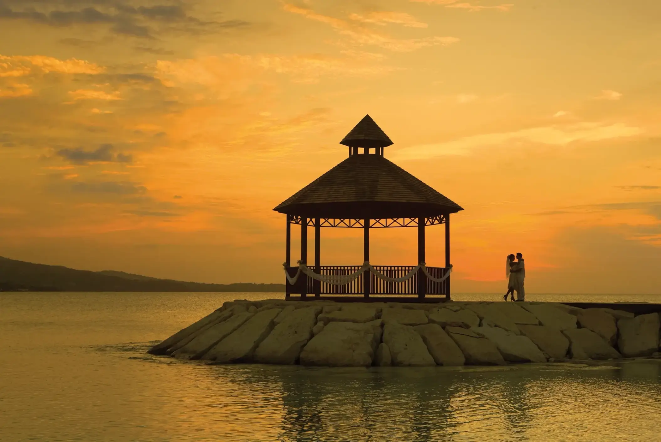 Silhouette of a couple by the oceanfront gazebo at Secrets Wild Orchid, Montego Bay during sunset
