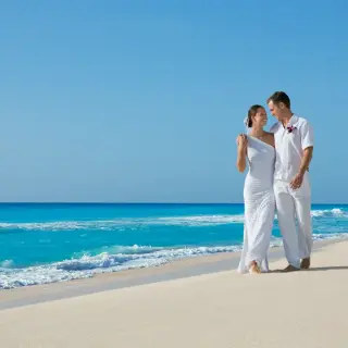 The bride and groom walking on the sand at Secrets Wild Orchid, Montego Bay