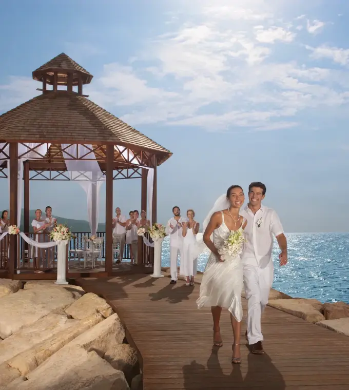 The bride and groom walking from an oceanfront gazebo ceremony at Secrets Wild Orchid, Montego Bay
