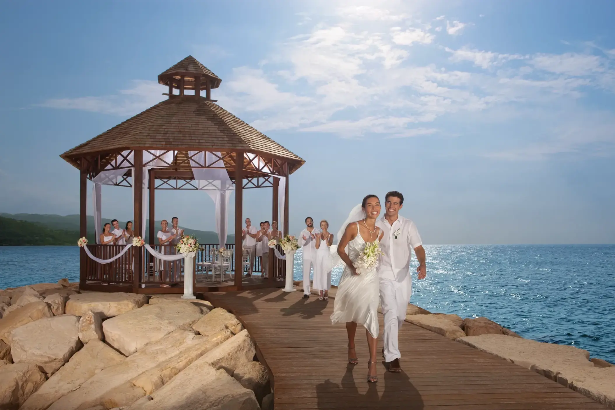 The bride and groom walking from an oceanfront gazebo ceremony at Secrets Wild Orchid, Montego Bay