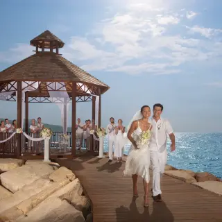 The bride and groom walking from an oceanfront gazebo ceremony at Secrets Wild Orchid, Montego Bay