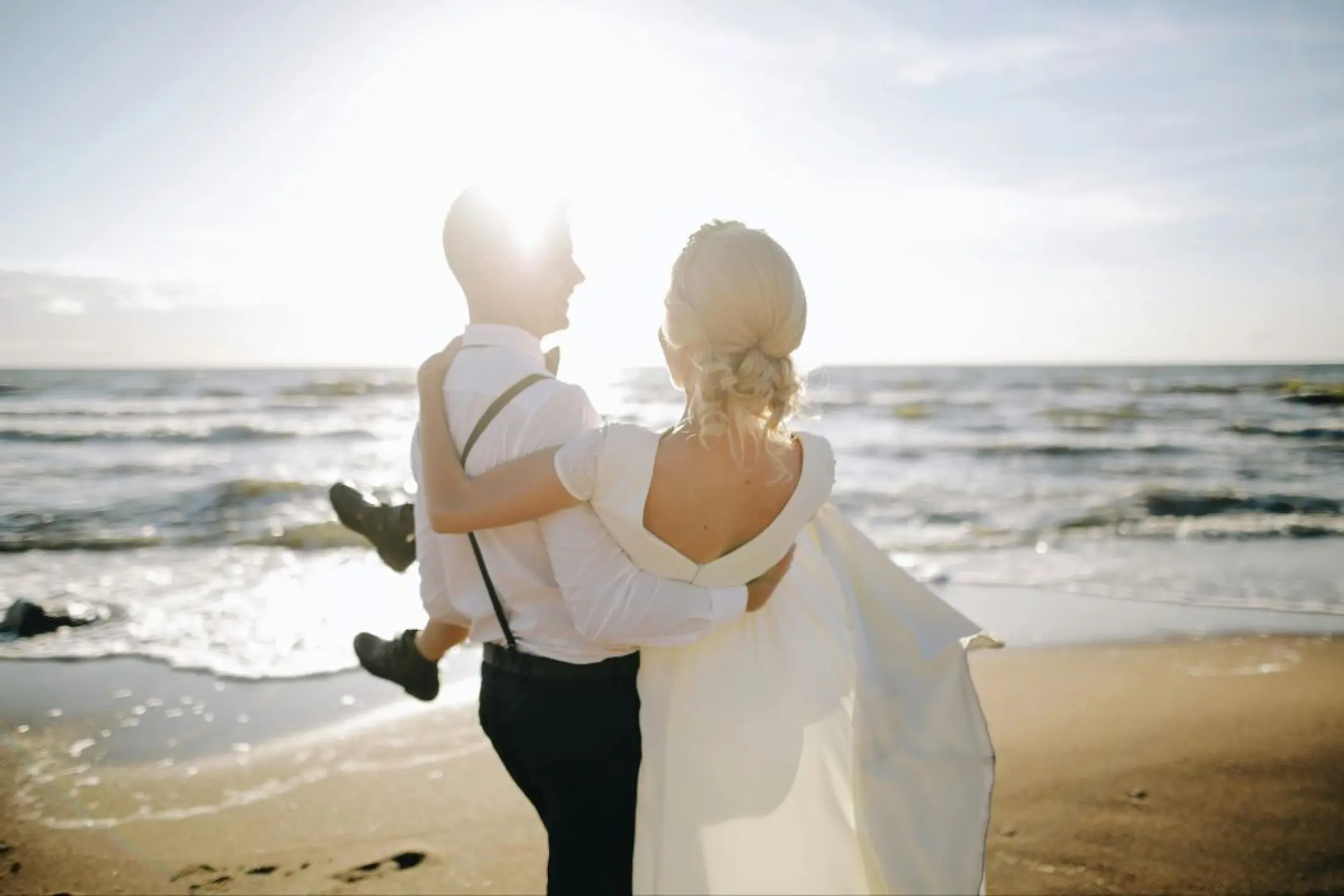Groom carrying the bride on the beach at sunset at SLS Playa Mujeres, Cancun