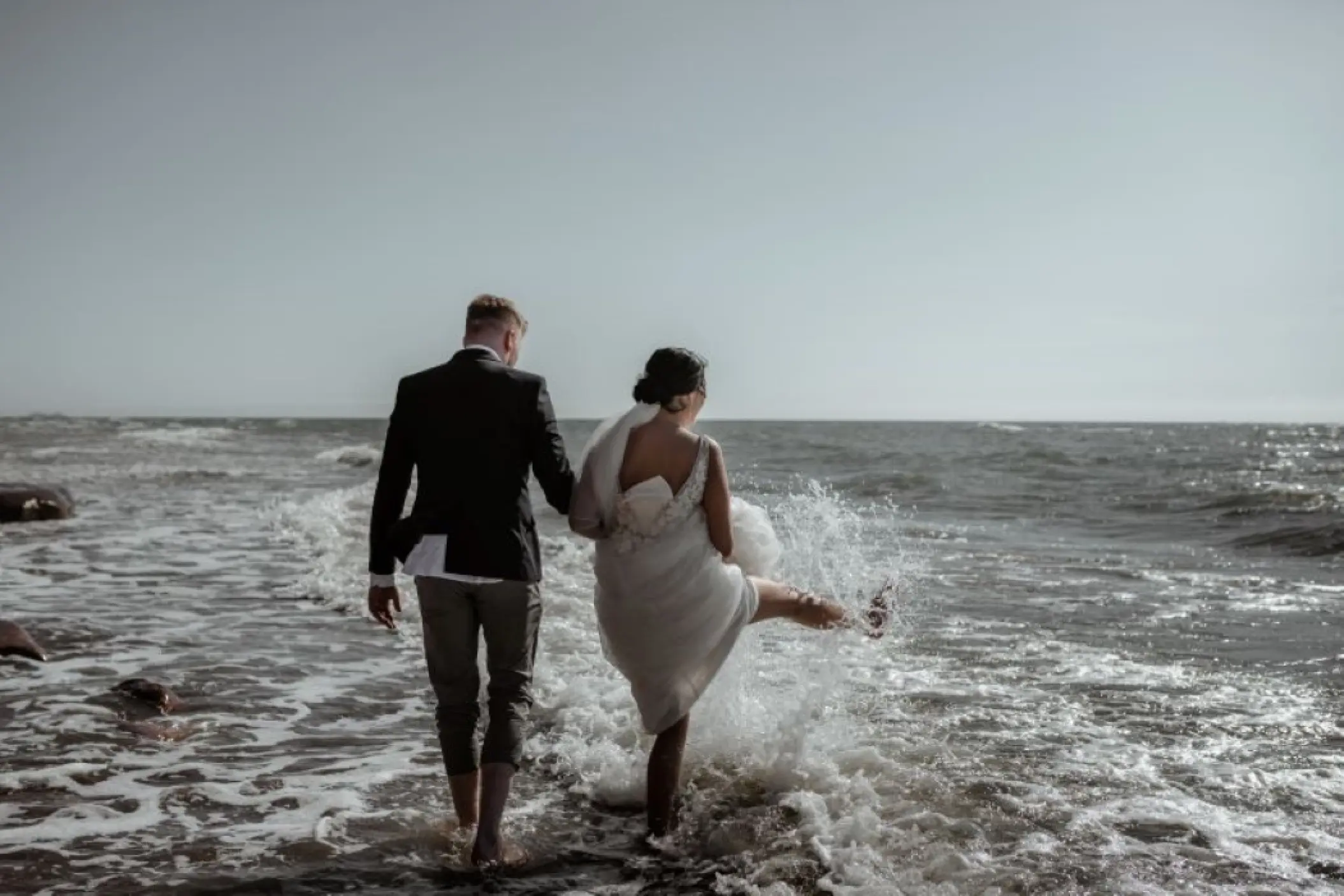 Bride and groom splashing in the waves at SLS Playa Mujeres, Cancun