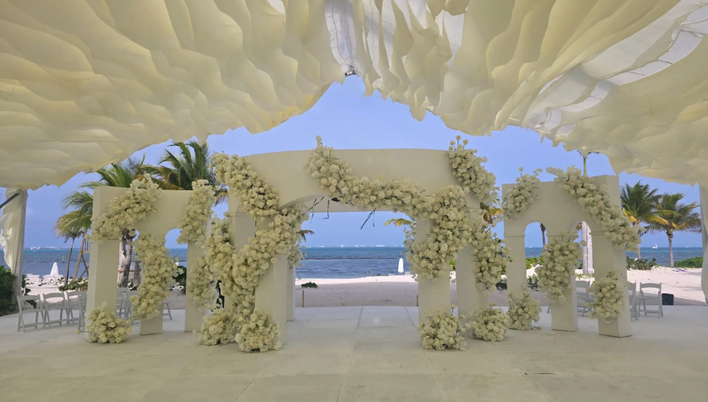 White archway wedding ceremony venue with floral decor at SLS Playa Mujeres, Cancun