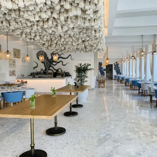 Cleo restaurant dining room with white textured ceiling and blue chairs at SLS Playa Mujeres, Cancun