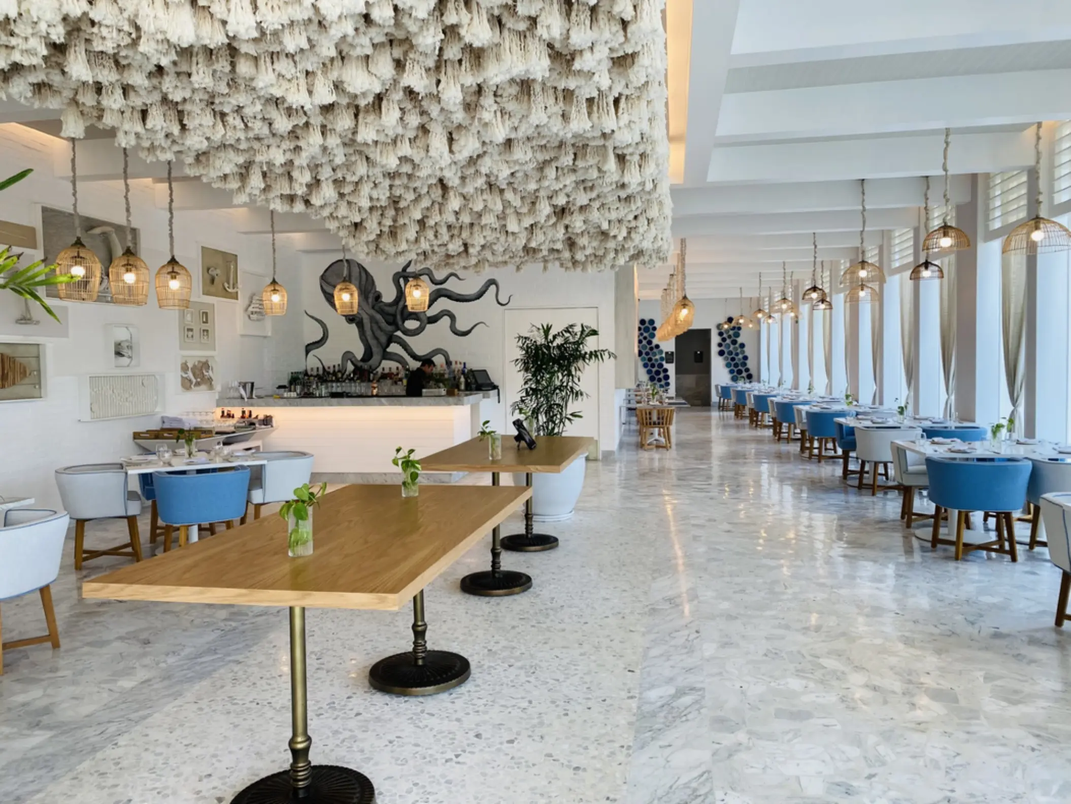 Cleo restaurant dining room with white textured ceiling and blue chairs at SLS Playa Mujeres, Cancun