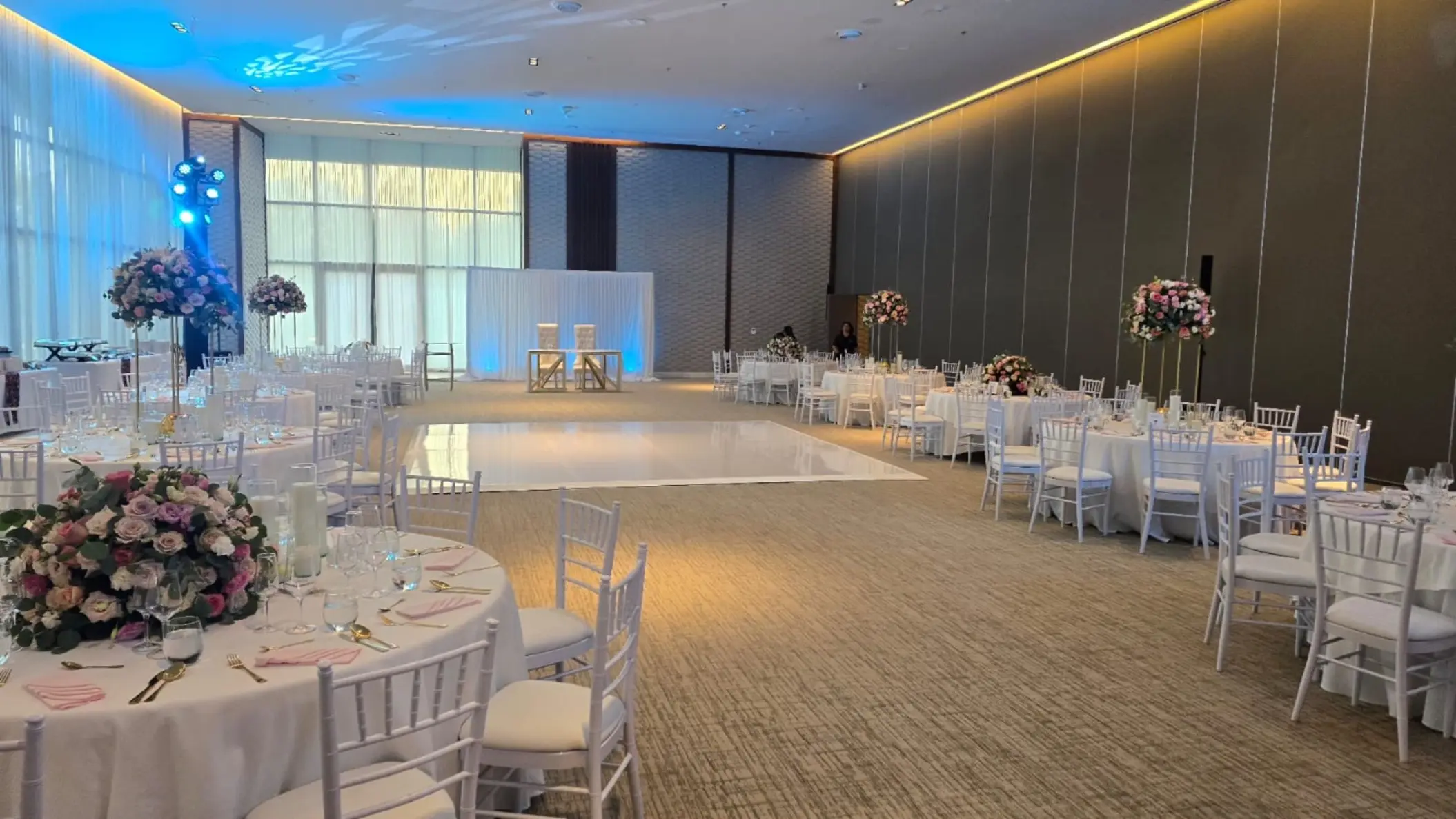 Grand Ballroom wedding reception with floral centerpieces and white dance floor at SLS Playa Mujeres, Cancun