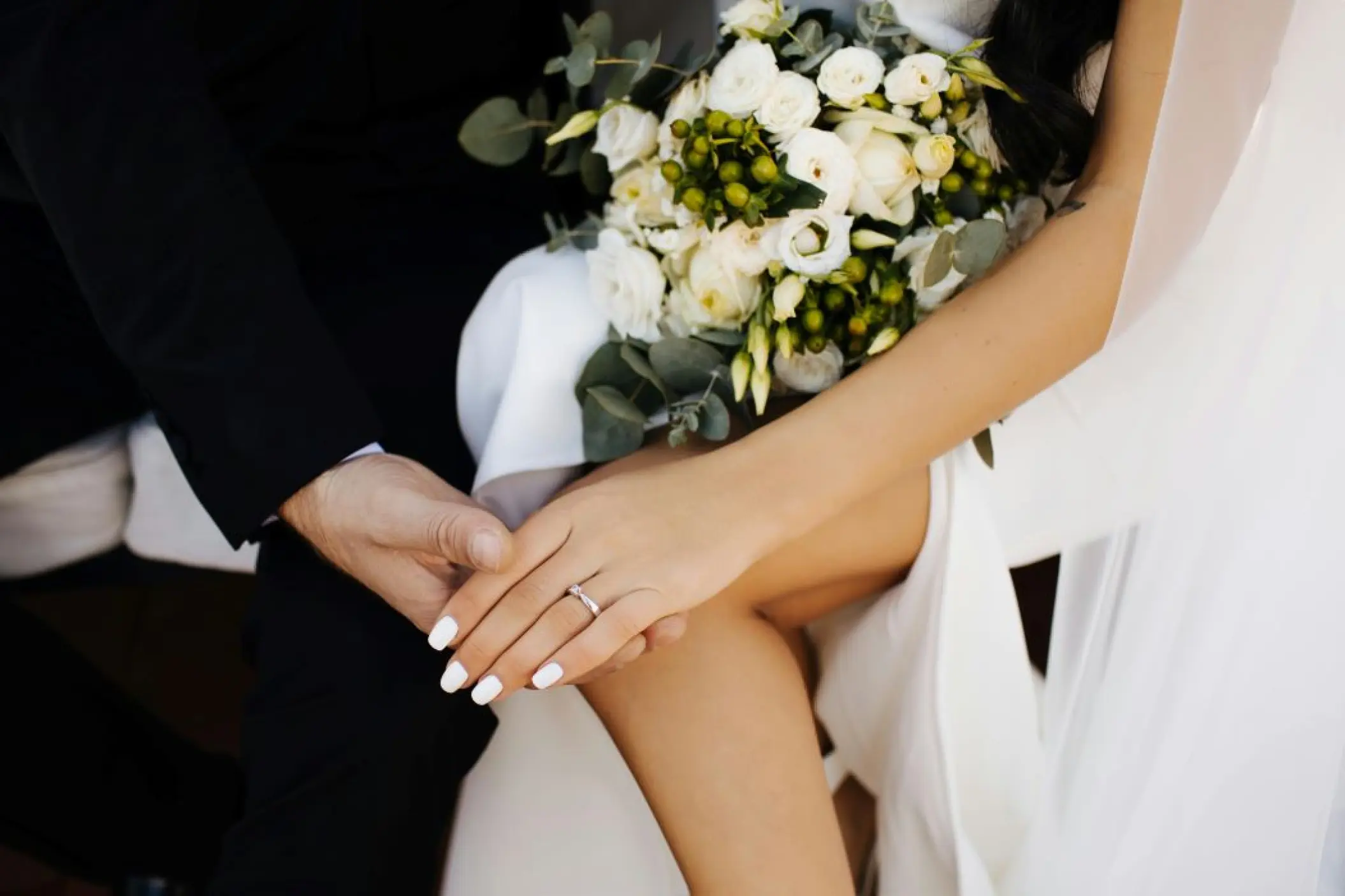 Close-up of a couple holding hands and a white flower bouquet at SLS Playa Mujeres, Cancun