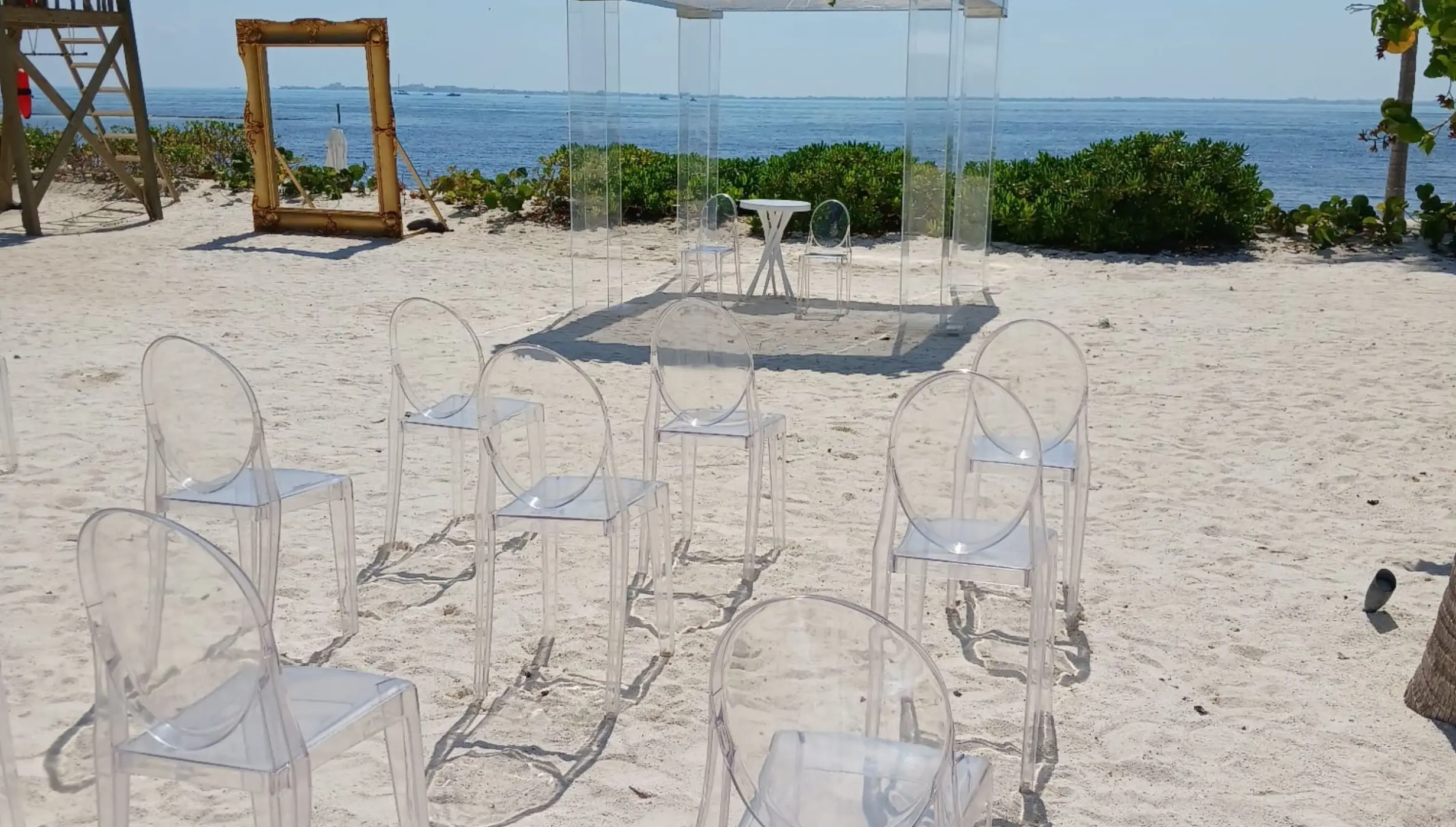 Beachfront wedding ceremony setup with clear acrylic chairs and huppah at SLS Playa Mujeres, Cancun
