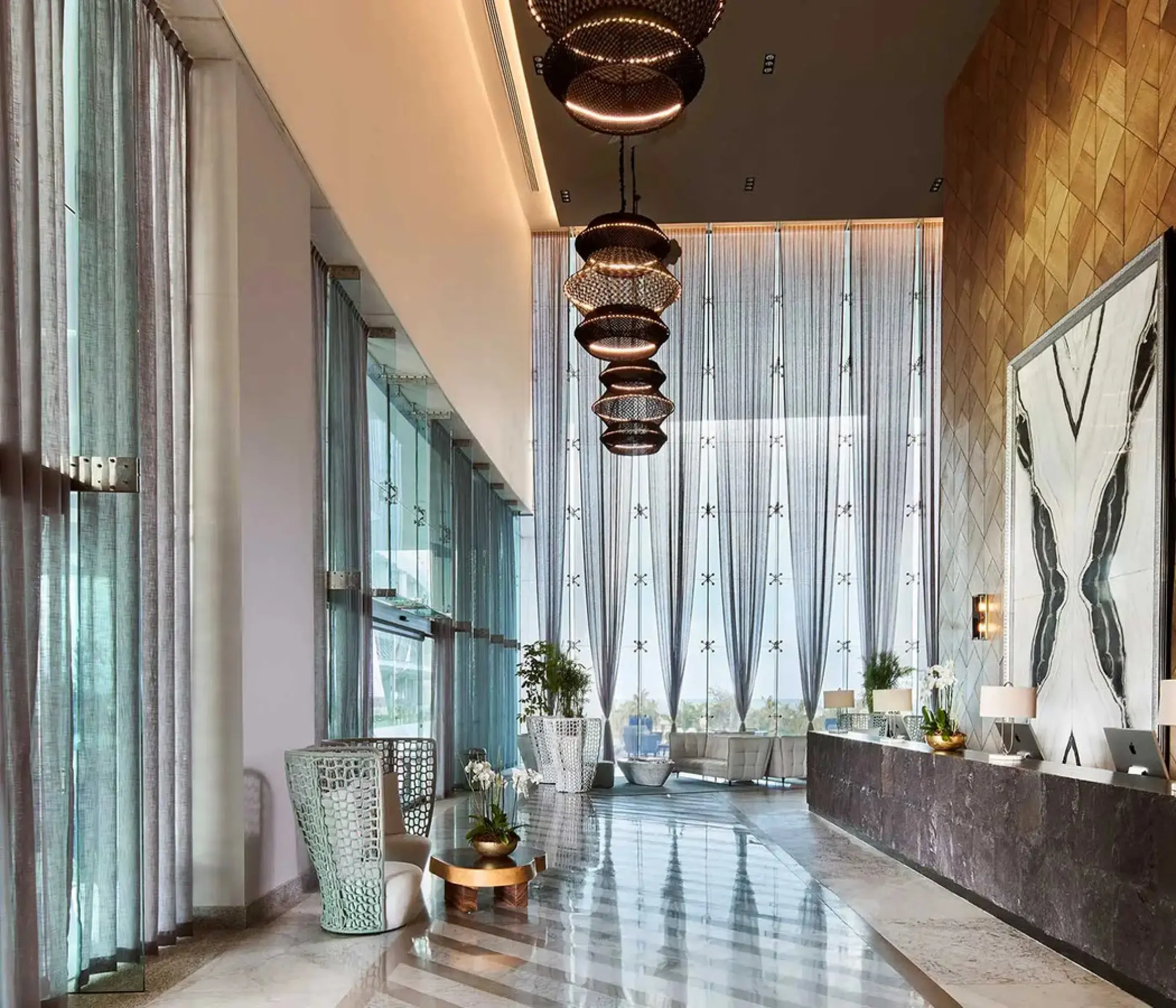 Modern lobby at SLS Playa Mujeres with tall windows and tiered pendant lights, Cancun
