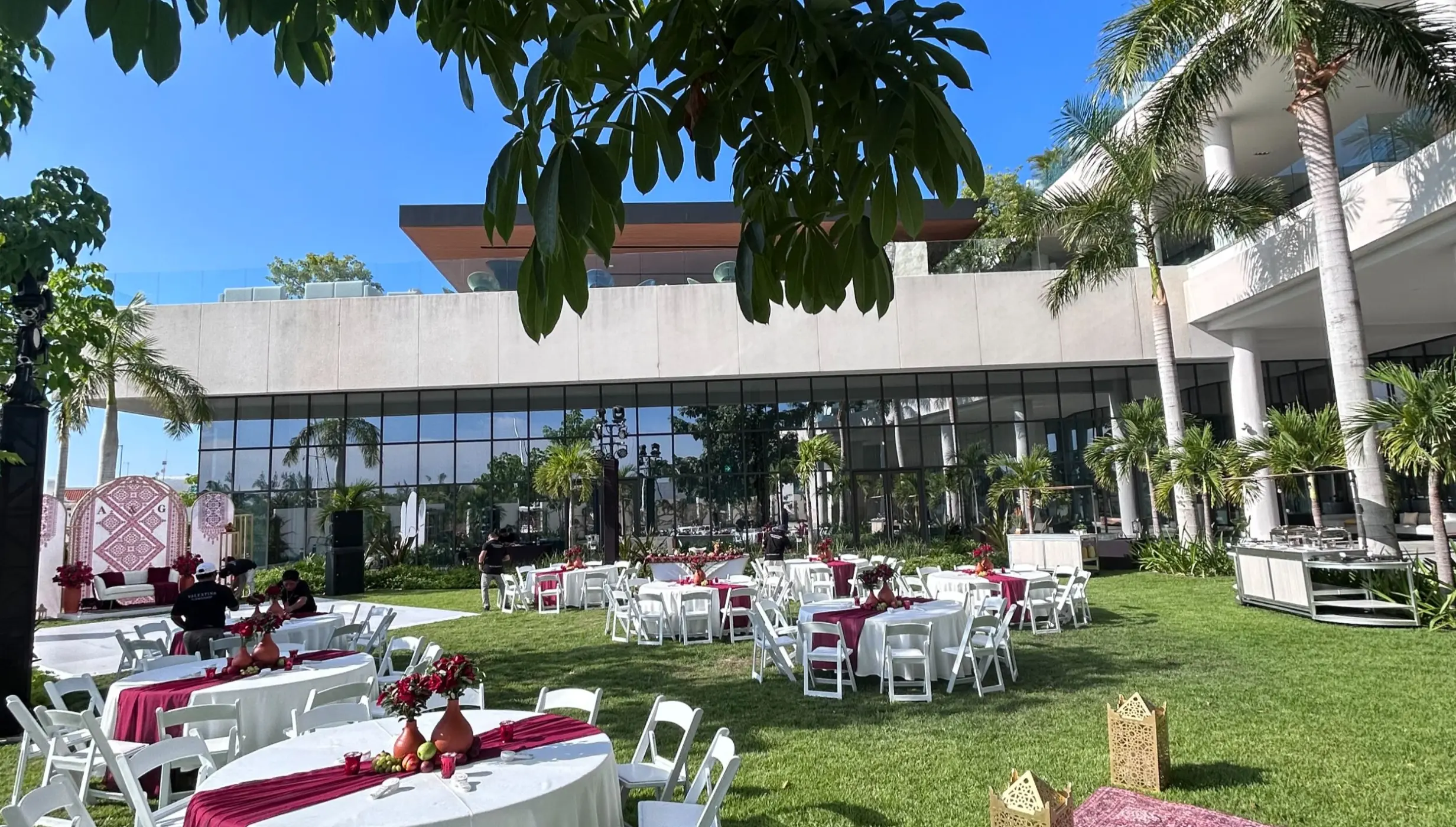Outdoor wedding reception with white tables and red runners on the Marina Lawn at SLS Playa Mujeres, Cancun