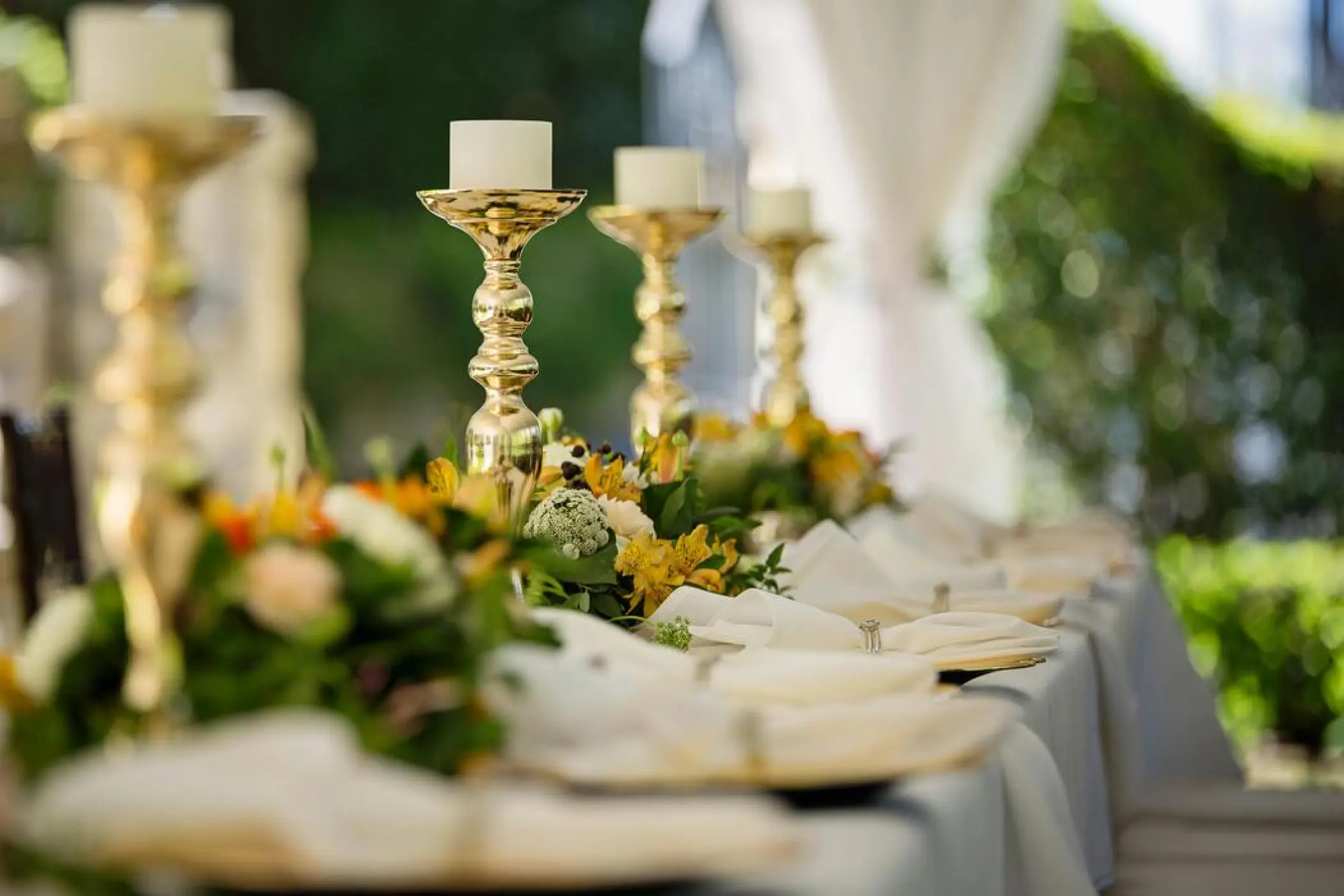 Wedding reception table with gold candelabras and yellow floral centerpieces at SLS Playa Mujeres, Cancun