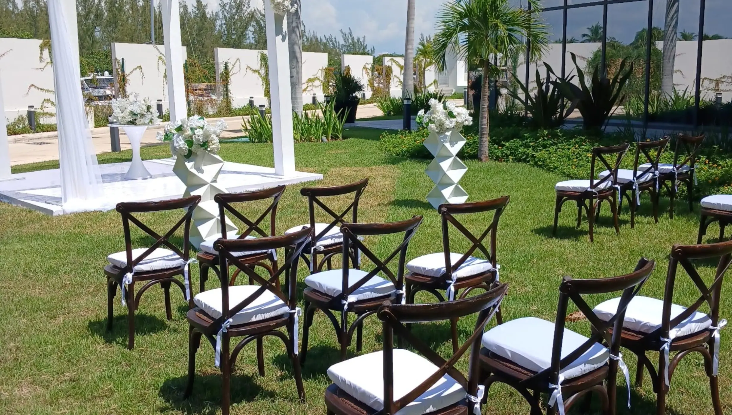 Lawn wedding ceremony setup with a white canopy and wooden chairs at SLS Playa Mujeres, Cancun