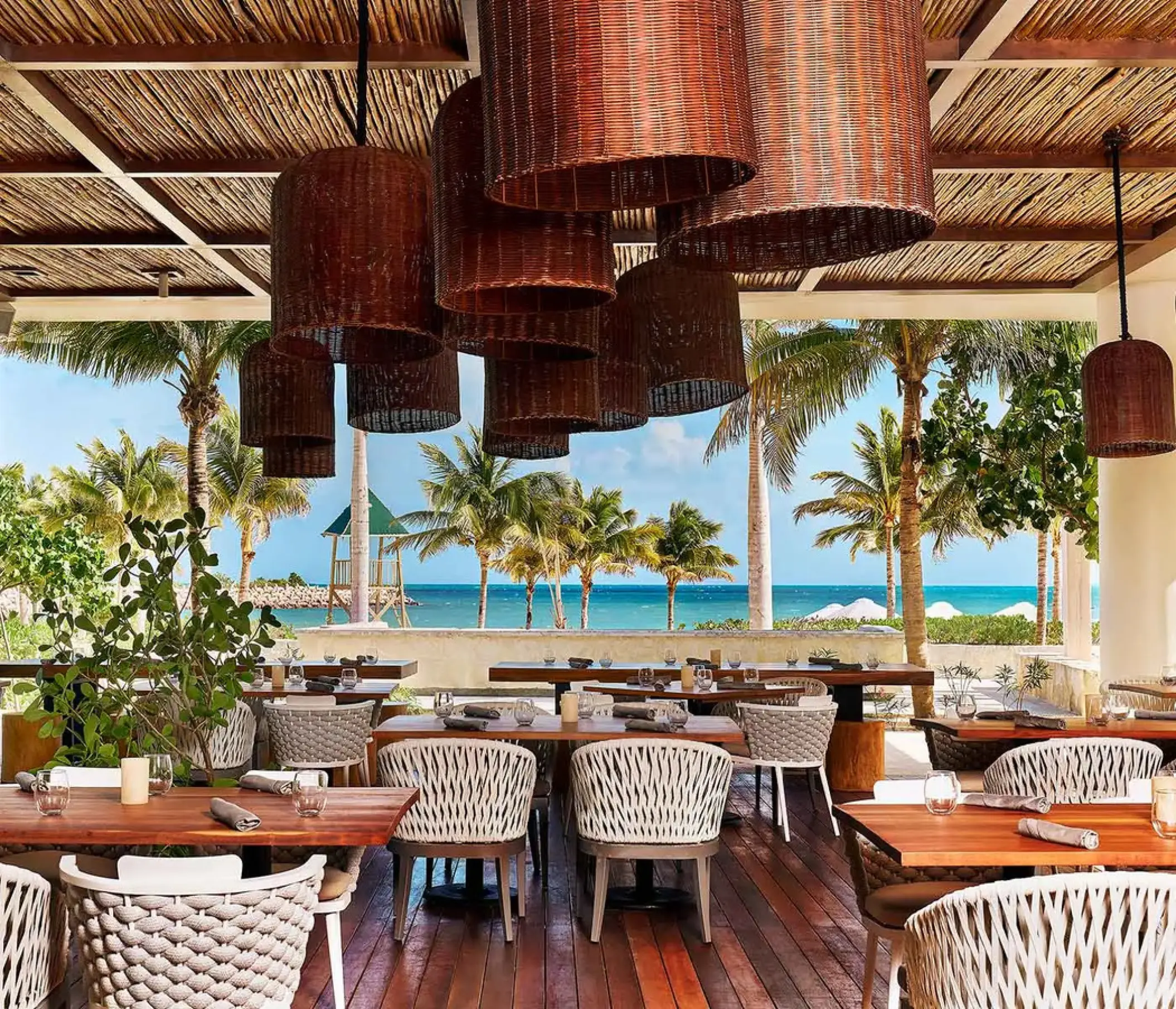 Open-air restaurant with woven light fixtures and ocean views at SLS Playa Mujeres, Cancun