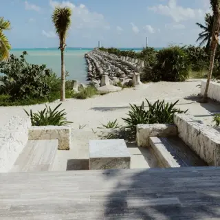 Stone seating area overlooking a stone pier and the turquoise sea at SLS Playa Mujeres, Cancun