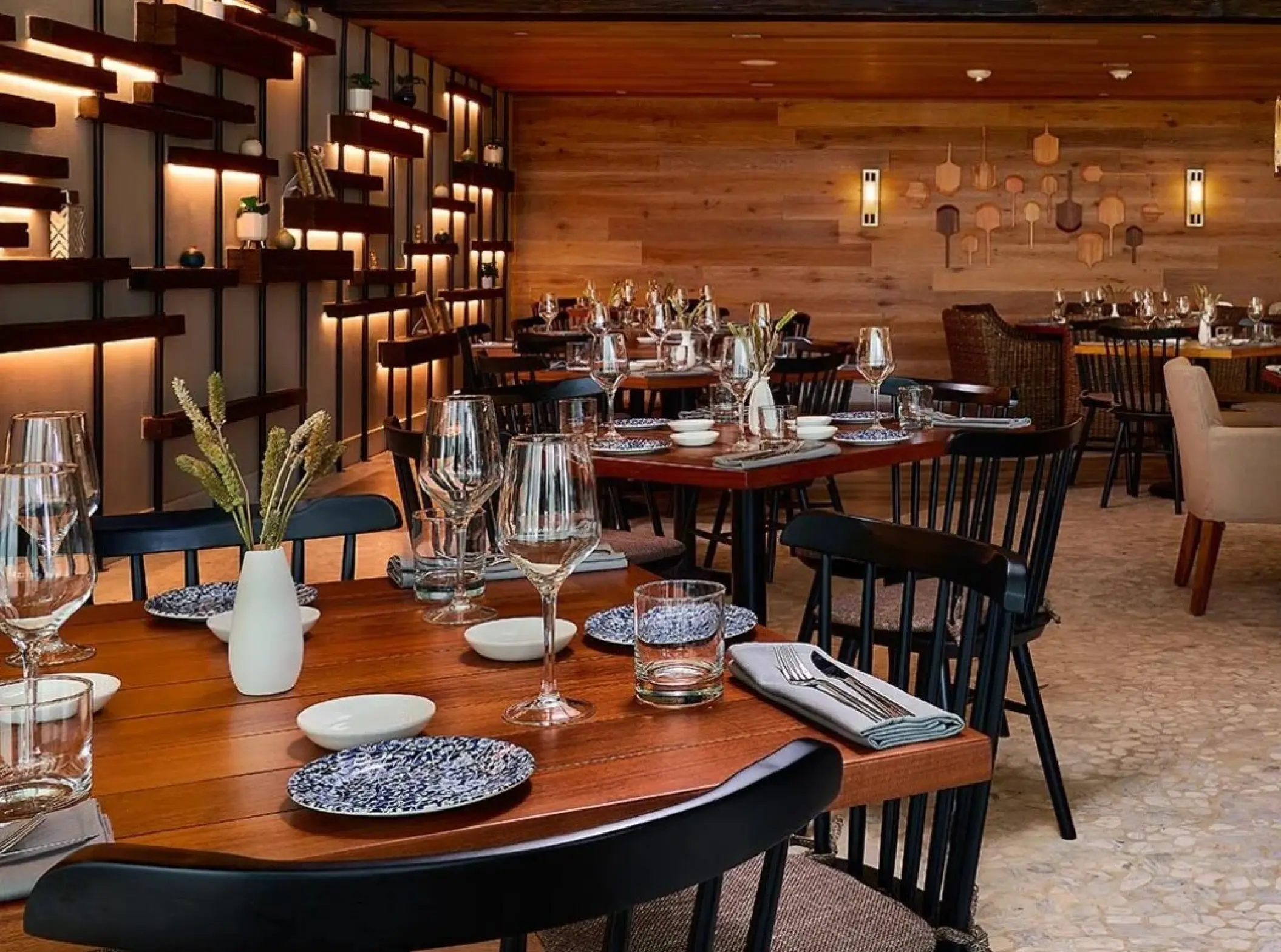 Fi'lia restaurant dining room with wooden tables and warm lighting at SLS Playa Mujeres, Cancun