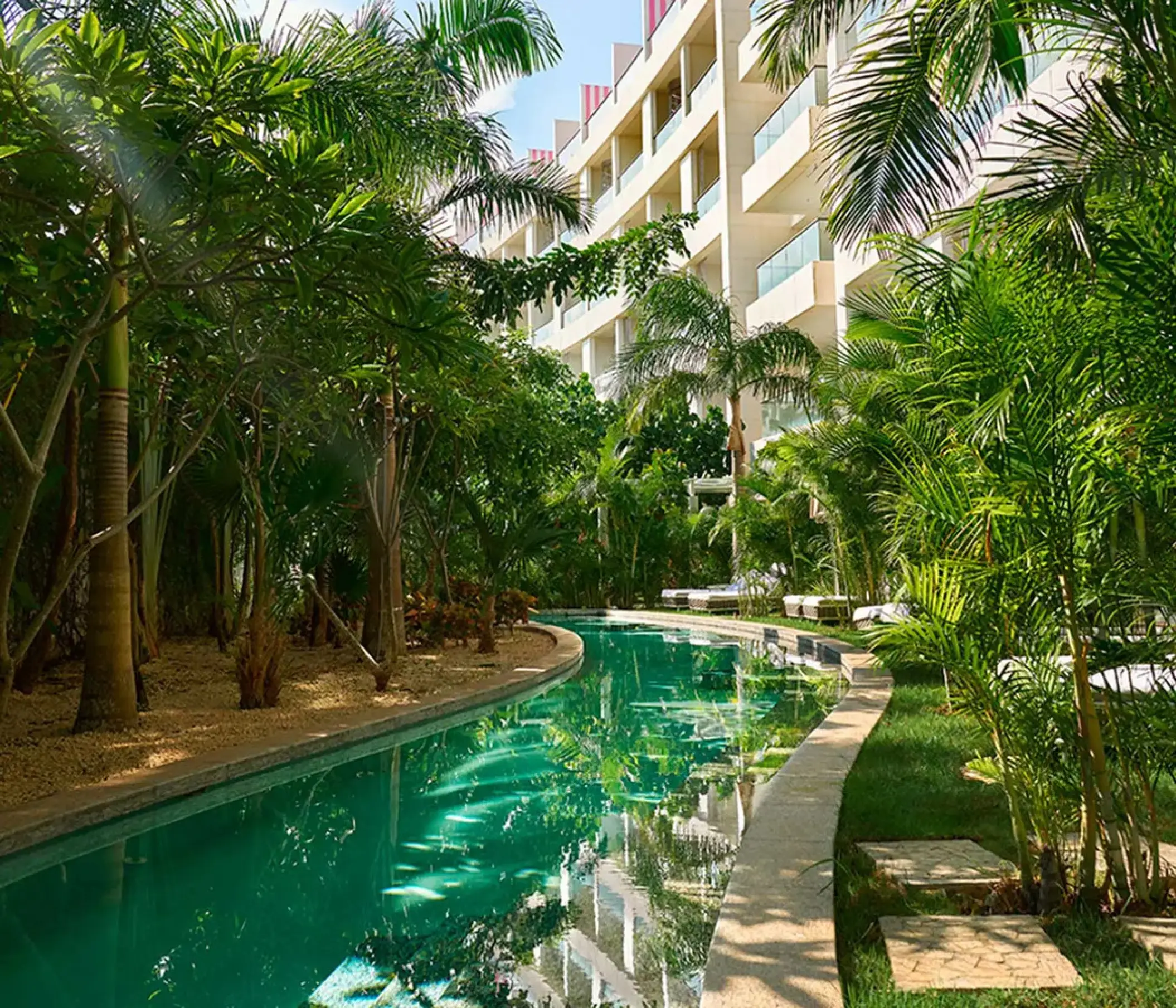 Swim-out pool winding through tropical greenery at SLS Playa Mujeres, Cancun