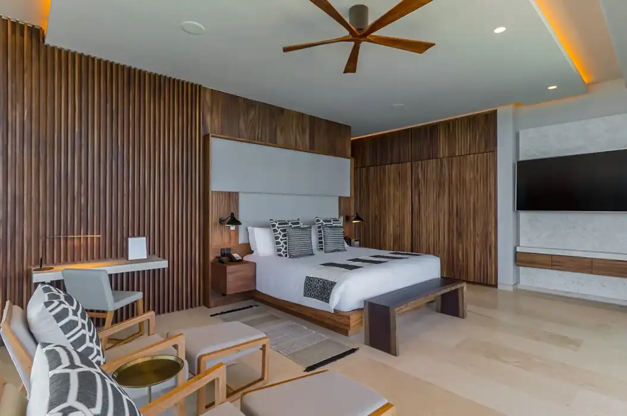 Solaz Los Cabos king bedroom with wood paneling and modern seating, Cabo San Lucas
