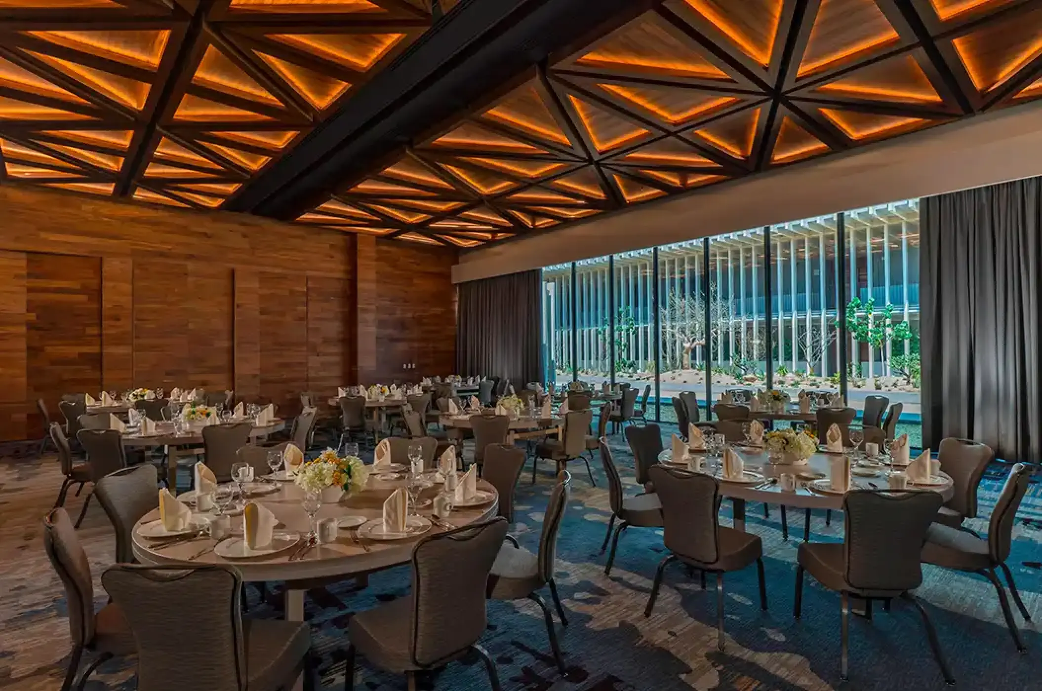 Indoor wedding reception with round tables and geometric ceiling at Solaz Los Cabos, Cabo San Lucas