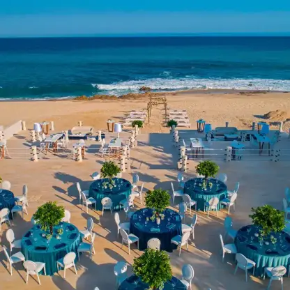 Beachfront wedding reception terrace with blue tables overlooking the ocean at Solaz Los Cabos, Cabo San Lucas