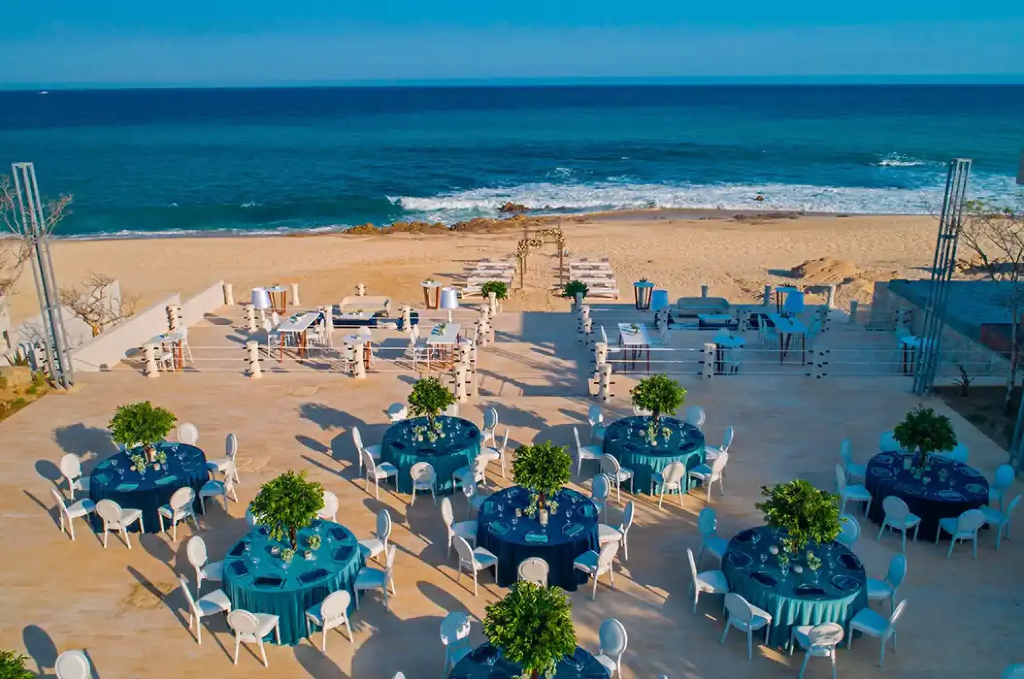 Beachfront wedding reception terrace with blue tables overlooking the ocean at Solaz Los Cabos, Cabo San Lucas
