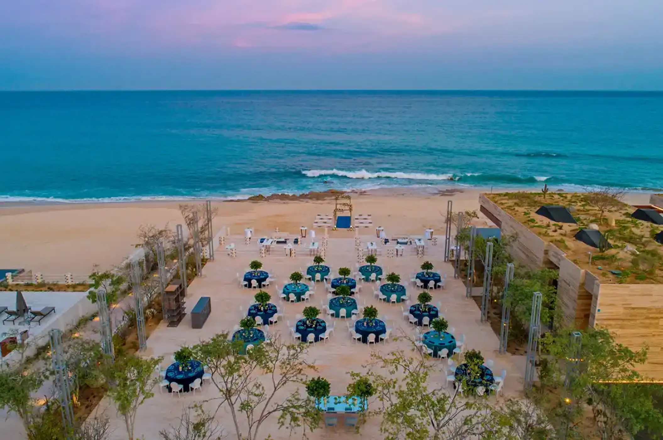 Outdoor wedding reception with blue table settings on the beach at Solaz Los Cabos, Cabo San Lucas