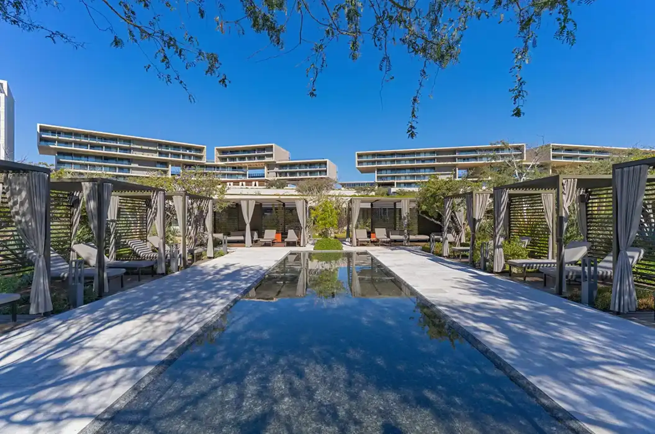 Private cabanas surrounding a modern courtyard pool at Solaz Los Cabos, Cabo San Lucas