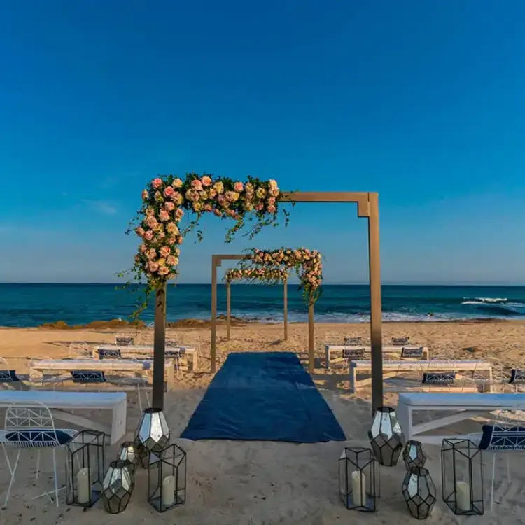 Beachfront wedding ceremony with floral arches and blue aisle runner at Solaz Los Cabos, Cabo San Lucas