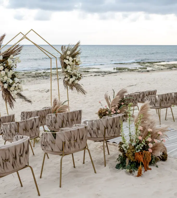 Beachfront wedding ceremony with a gold arch and pampas grass at The Beachfront by The Fives, Playa Del Carmen