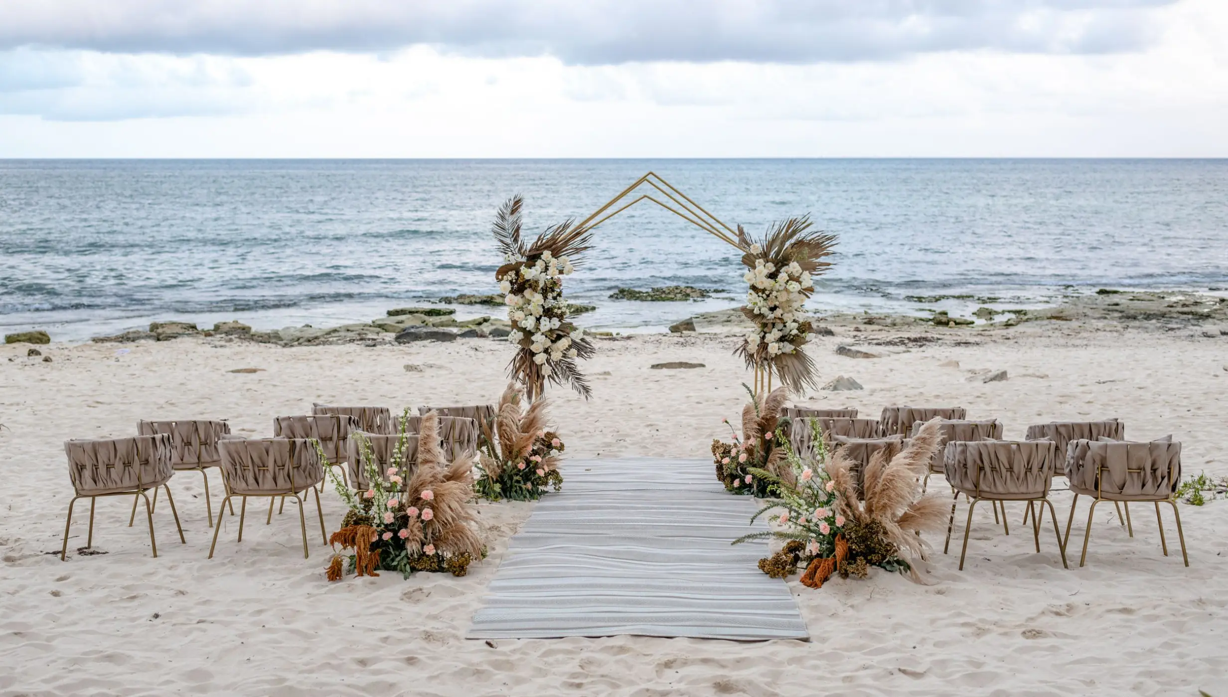 Beachfront wedding ceremony with a floral arch and wooden aisle at The Beachfront by The Fives, Playa Del Carmen