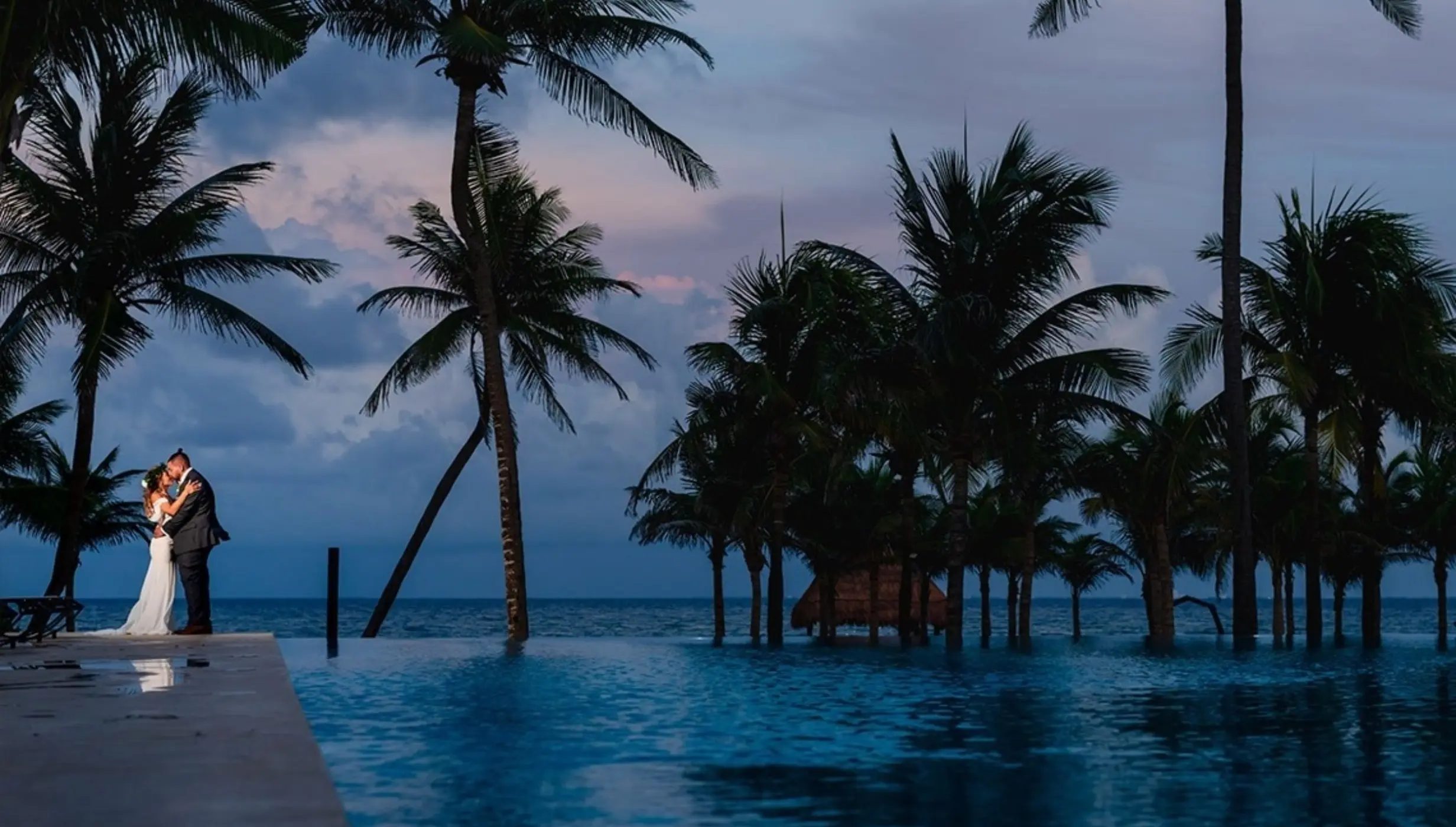 Bride and groom embrace by the infinity pool at The Beachfront by The Fives, Playa Del Carmen