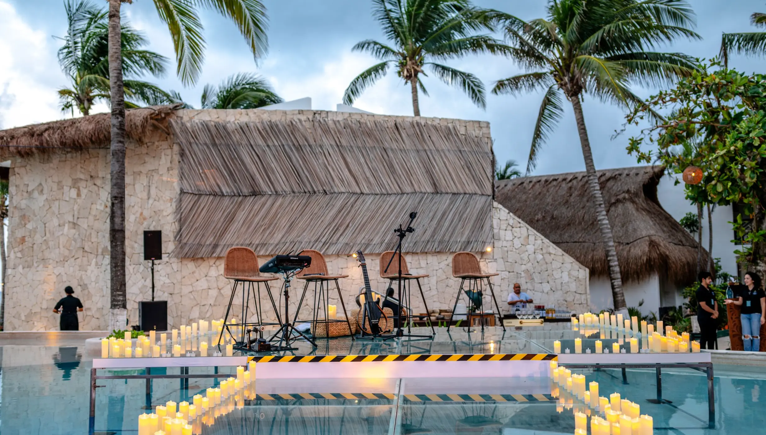 Pool terrace wedding reception setup with candles and live music stage at The Beachfront by The Fives, Playa Del Carmen