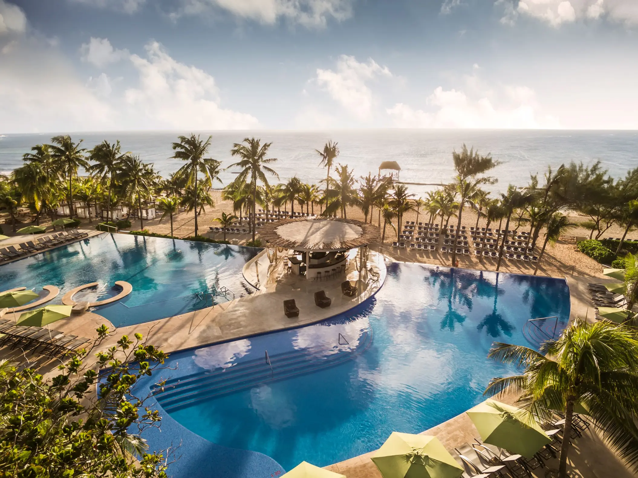 Aerial view of the beachfront swimming pool and swim-up bar at The Fives Beach Hotel, Playa Del Carmen