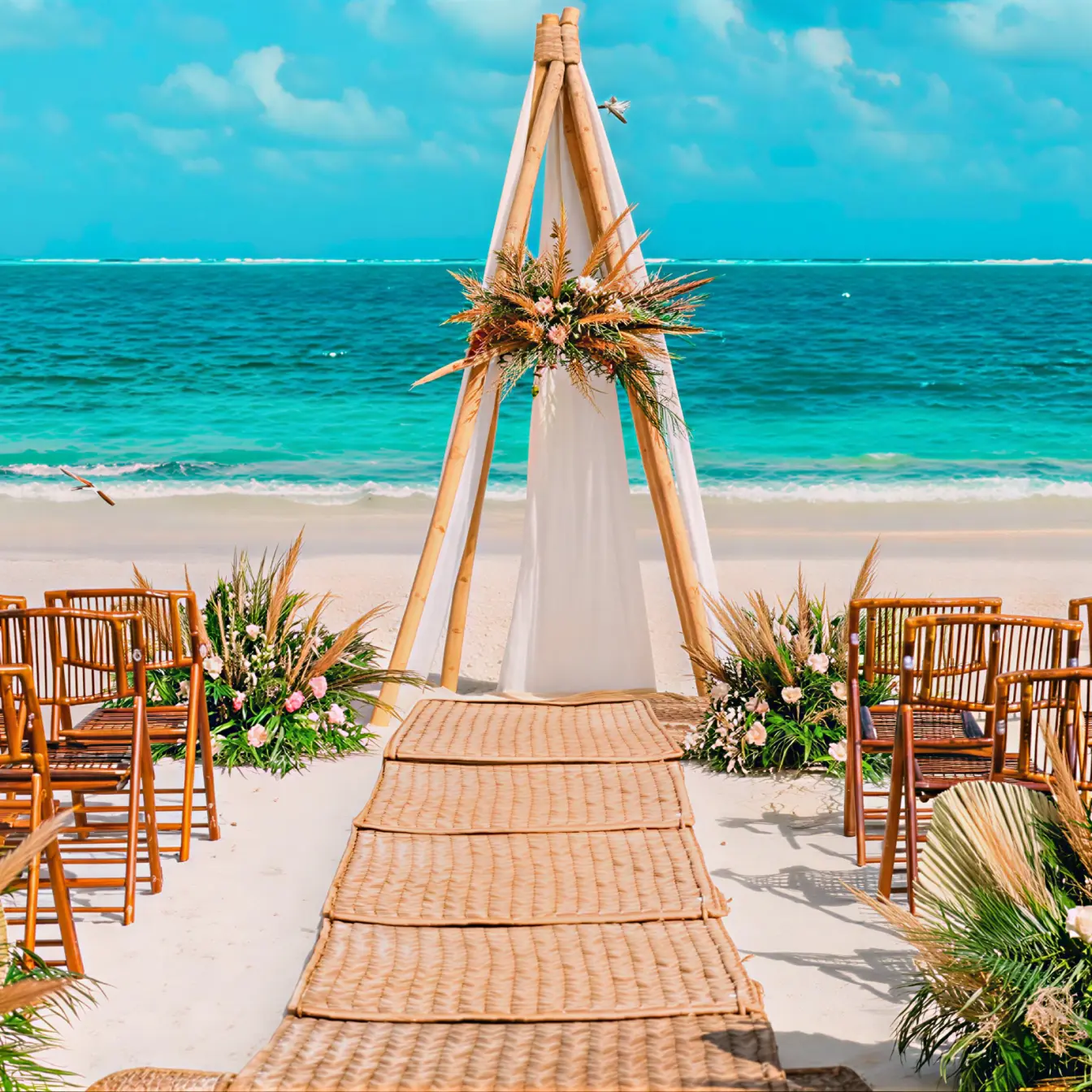 Beachfront wedding ceremony with a wooden teepee arch and woven aisle at The Fives Oceanfront, Mexico