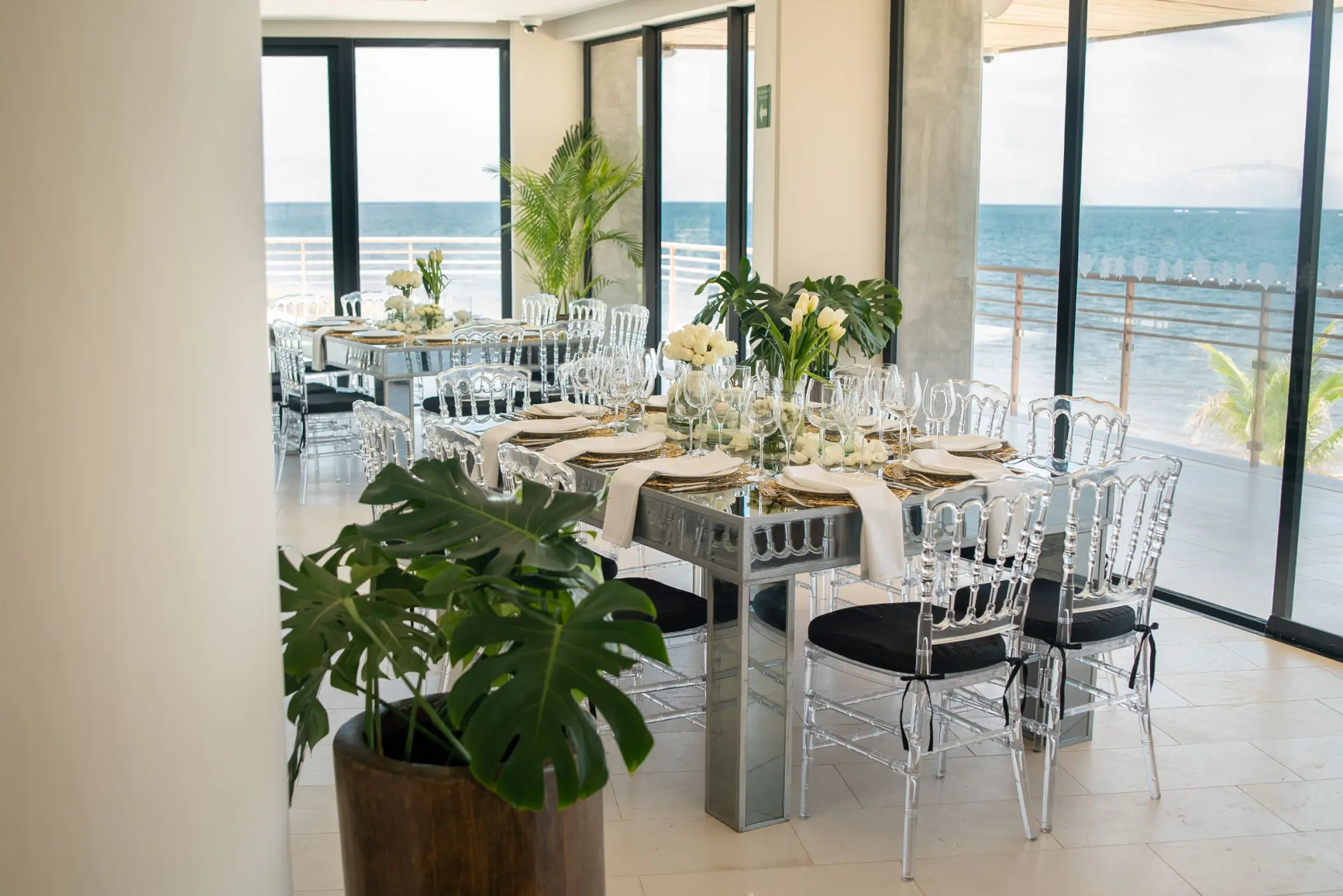 Indoor wedding reception with mirrored tables and ocean views at The Fives Oceanfront, Riviera Maya