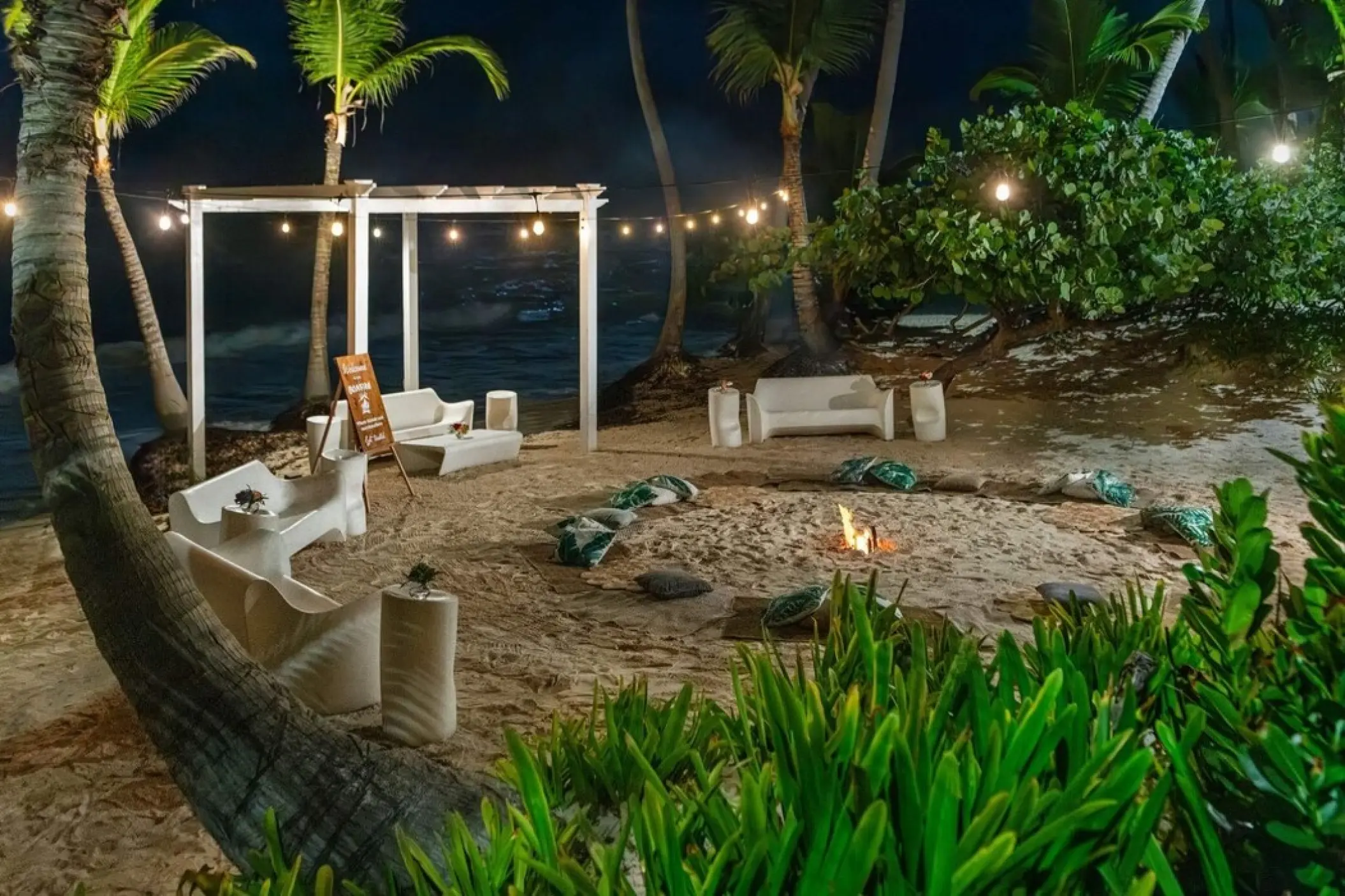 Nighttime beach wedding reception lounge with string lights and a fire pit at TRS Turquesa, Punta Cana