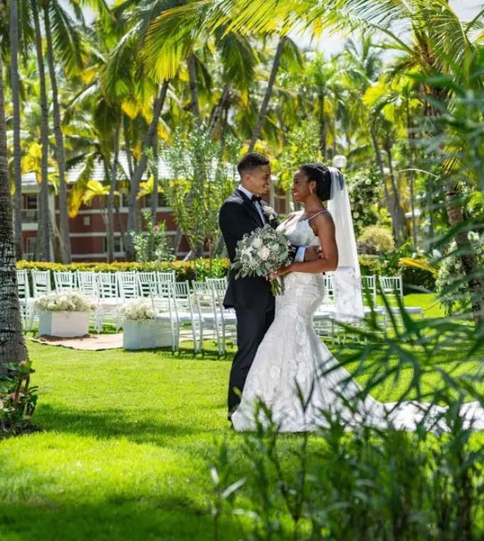 The bride and groom standing in a lush garden during their wedding ceremony at TRS Turquesa, Punta Cana