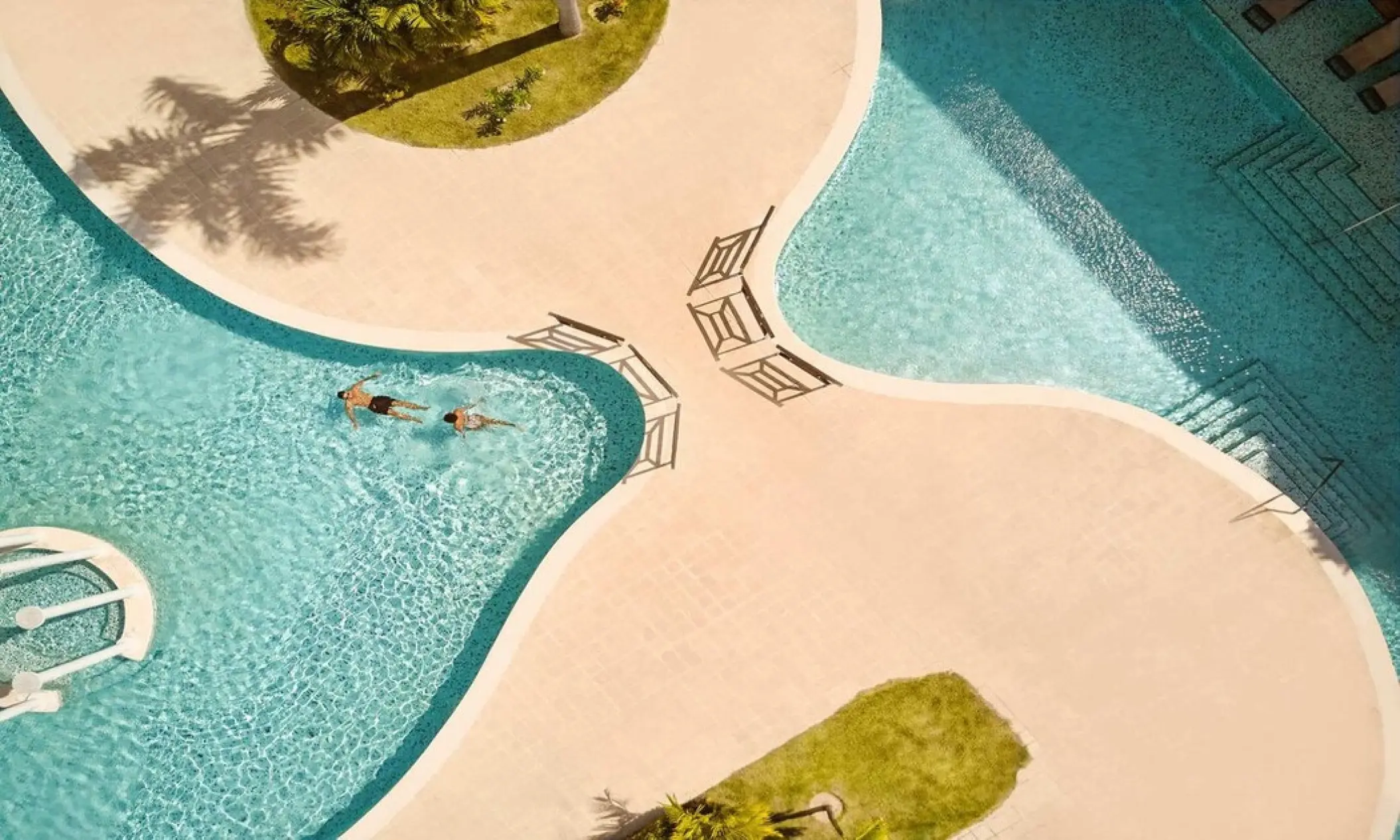 Aerial view of a couple swimming in the turquoise winding pool at TRS Turquesa, Punta Cana