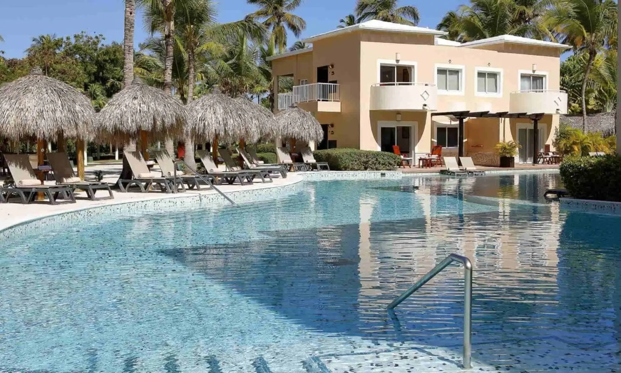 TRS Turquesa outdoor swimming pool with lounge chairs and thatched umbrellas, Punta Cana