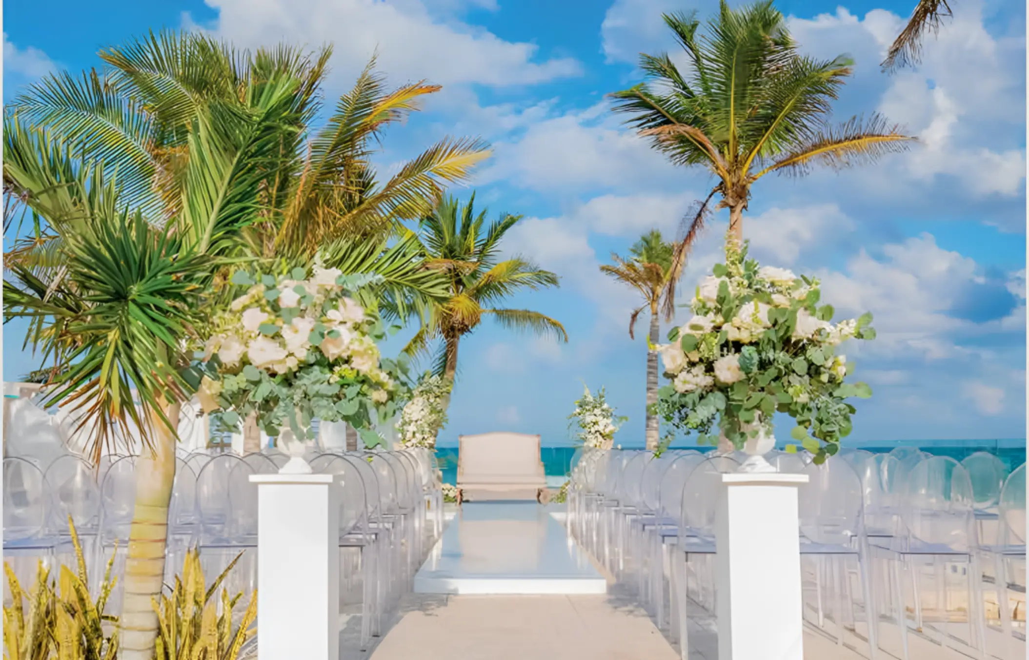 Gaia Terrace wedding ceremony setup with white floral arrangements and ghost chairs at TRS Yucatan, Riviera Maya