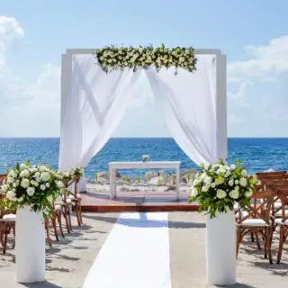 Oceanfront wedding ceremony with white floral arch at TRS Yucatan, Riviera Maya