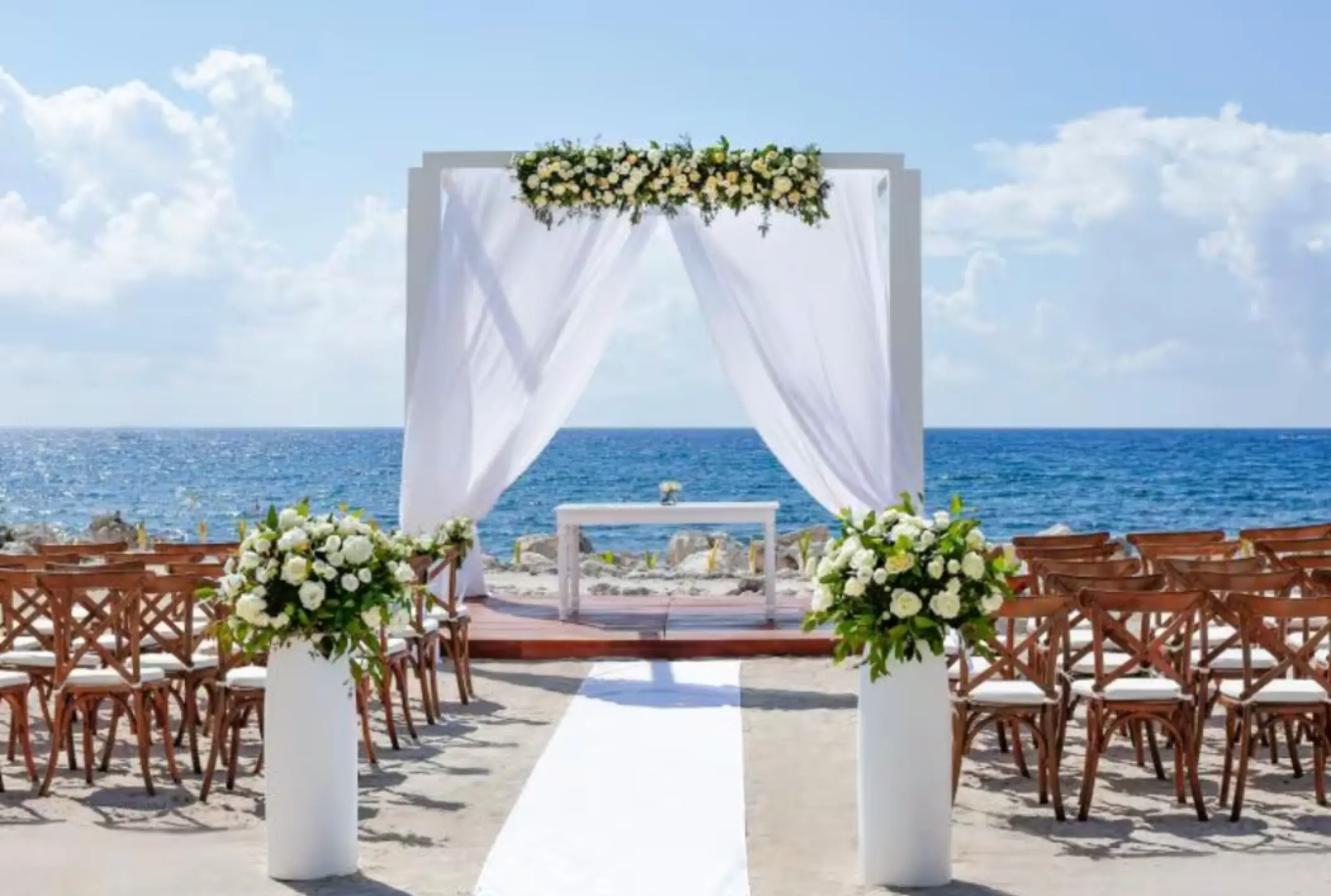 Oceanfront wedding ceremony with white floral arch at TRS Yucatan, Riviera Maya
